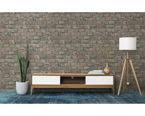 Woonkamer met tv-meubel, vloerlamp en bakstenen muur