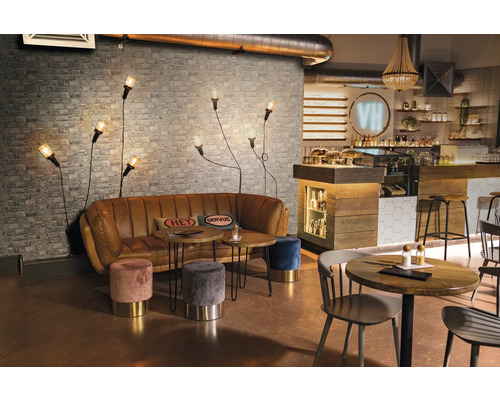 Interieur van een café met bank, tafels, krukken en wandlampen voor een bakstenen muur