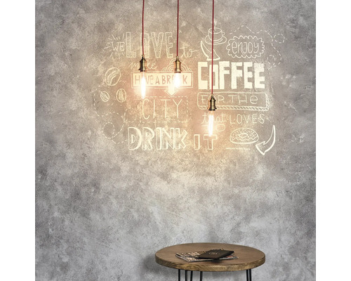 Drie hanglampen boven een kleine tafel voor een muur met koffiemotieven