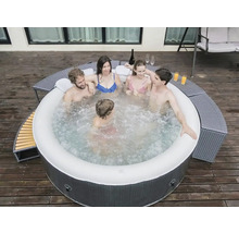 Opblaasbare jacuzzi met vijf personen op een houten terras met drankjes en zitplaatsen.