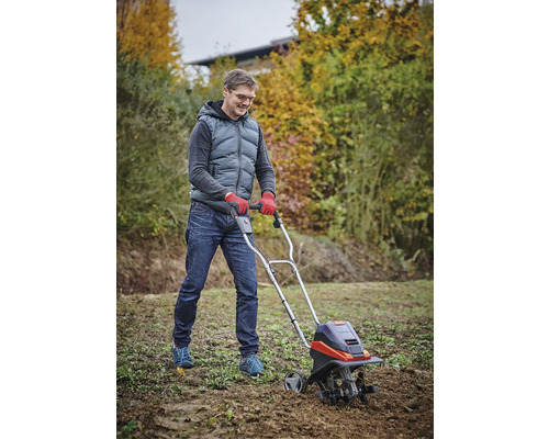 Man werkt met een tuinfrees in de tuin.