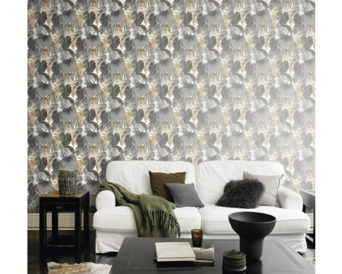 Woonkamer met bank voor een muur met bladerbehang