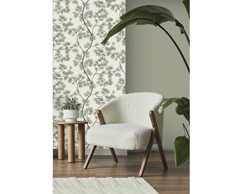 Scène met bloemenbehang, fauteuil, bijzettafel, vloerkleed en kamerplant.