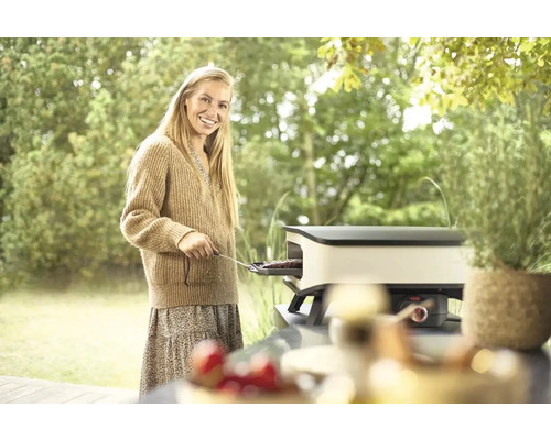 Vrouw grilt op een tafelgrill in de tuin.