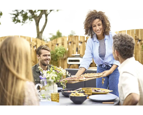 Een vrouw serveert pizza op een tuinevenement met vrienden.