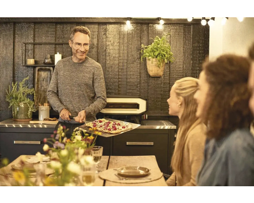 Man met pizza voor pizzaoven in de eetkamer