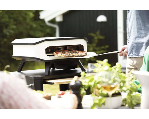 Pizzaoven met pizza en pizzaschep buiten