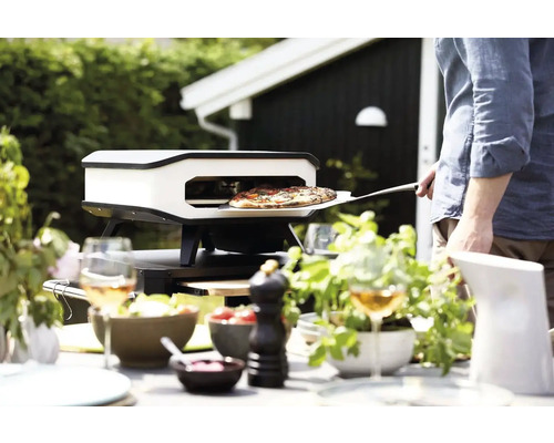 Pizzaoven in de tuin met bereide pizza op pizzaschep