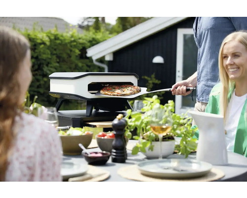 Pizzaoven in de tuin met mensen die pizza bakken