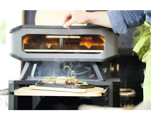 Een grilloven met een persoon die kruiden over een gerecht strooit.