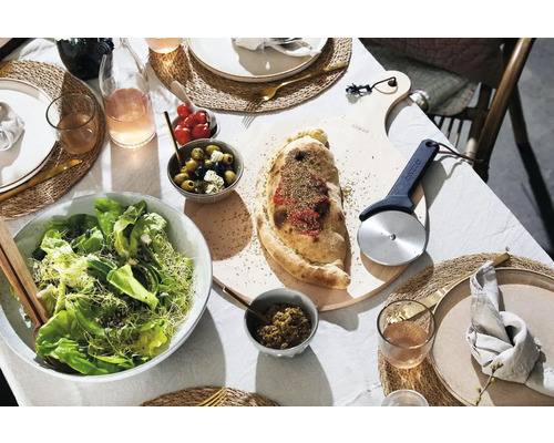 Gedekte tafel met calzone, salade, olijven en pizzasnijder