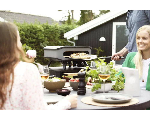 Buitenscène met pizzaoven, tafel en mensen