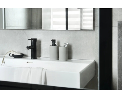 Wastafel met kraan, zeepdispenser en tandenborstelbeker in de badkamer.