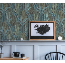 Decoratieve wand met behang met varenpatroon, een ingelijste IJsland poster en decoratieve objecten
