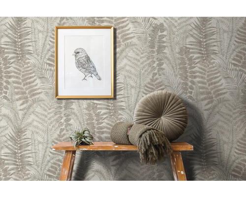 Scene met behang met varenmotief, ingelijste vogelafbeelding, rond kussen en decoratie op een houten kruk