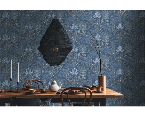 Een eetkamer met een houten tafel, servies, een hanglamp en een bloemenbehang.