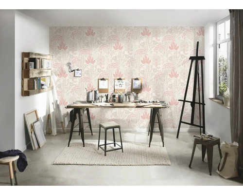 Een lichte studio met een patroonbehang, een houten tafel en diverse kunstbenodigdheden.