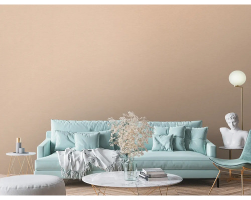 Woonkamer met bank, stoel, decoratie en beige wandbekleding.