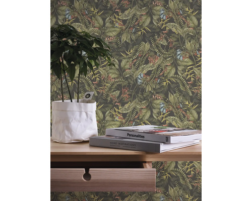 Close-up van een muur met een junglebehang met planten en bloemen, aangevuld met een plant in een pot en boeken op een houten tafel.