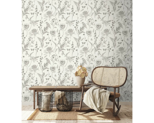 Decoratieve kamer met behang met vogel-, bloem- en vlindermotieven, een vloerkleed, een bank, manden en een schommelstoel.