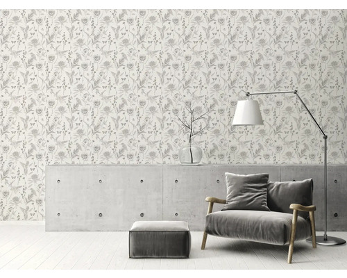 Kamerbeeld met een behang met bloemenmotief, een fauteuil, een vloerlamp en een salontafel.