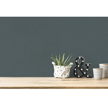 Close-up van een wandbehang met kamerplant, decoratieve ampersand en twee bekers op een tafel