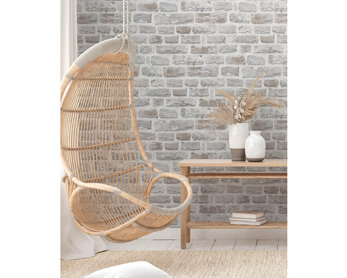 Rotan hangstoel in een lichte, vriendelijke kamer met bakstenen behang