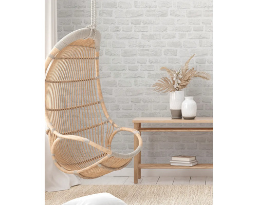 Rotan hangstoel, wandrek en decoratieve vazen in een lichte kamer.
