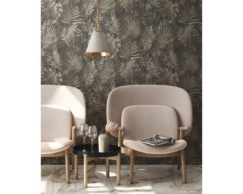 Woonkamer met behang met bladerpatroon, twee fauteuils, een bijzettafel, een lamp en decoraties.