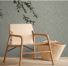 Lichtgekleurde fauteuil van hout en leer naast een mand voor een muur met planten