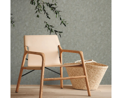 Lichtgekleurde fauteuil van hout en leer naast een mand voor een muur met planten
