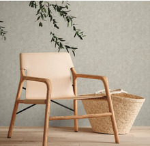 Interieurfoto van een woonkamer met een fauteuil met houten frame, een rieten tas en groene bladeren