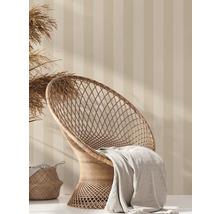 Decoratieve scène met rotan stoel, deken en mand tegen een gestreepte wand