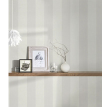 Interieurfoto van een kamer met gestreept behang, versierd met een houten plank, fotolijsten en een lamp