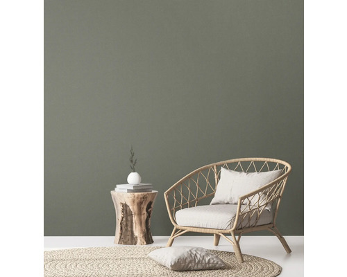 Woonkamer met rotan stoel, houten bijzettafel en rond tapijt