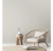 Licht interieur met rotan stoel, rond vloerkleed en houten bijzettafel.