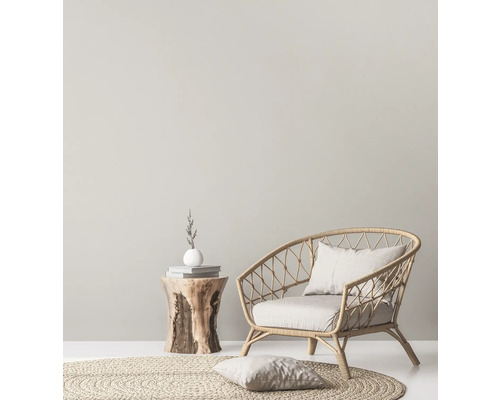 Licht interieur met rotan stoel, rond vloerkleed en houten bijzettafel.