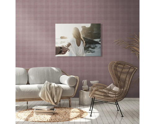 Woonkamer met bank, stoel, bijzettafel, tapijt en een muurkunstwerk met een paar op het strand.