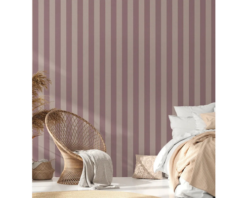 Slaapkamer met gestreept behang, rotan stoel en bed.