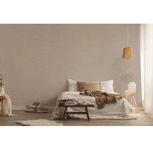 Lichte slaapkamer met bed, houten kruk en hanglamp van rotan voor een vriendelijke sfeer.