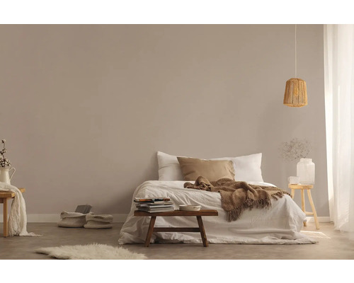 Lichte slaapkamer met bed, houten kruk en hanglamp van rotan voor een vriendelijke sfeer.