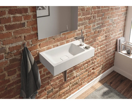 Badkamer met wastafel, spiegel en handdoek aan een bakstenen muur