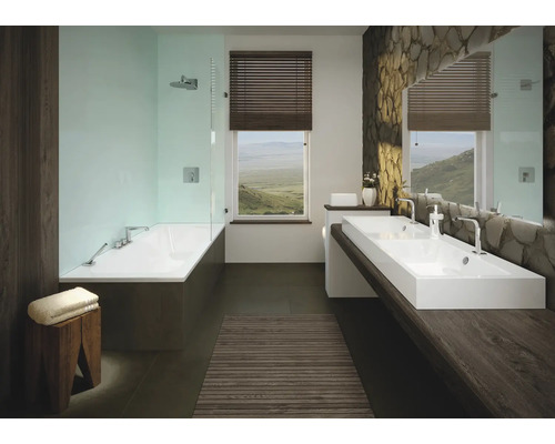 Badkamer met bad, twee wastafels en stenen muur