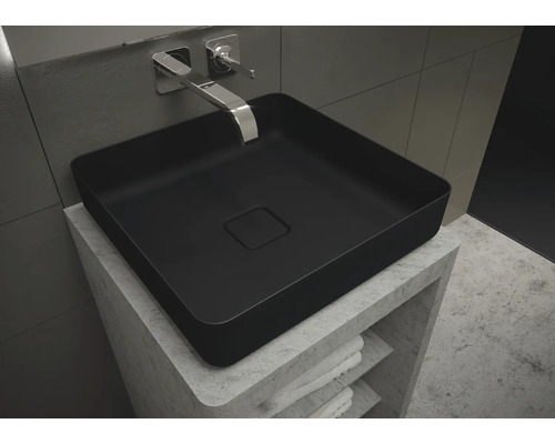 Zwarte opzetwastafel op een wastafelmeubel met opbergvakken en handdoeken.