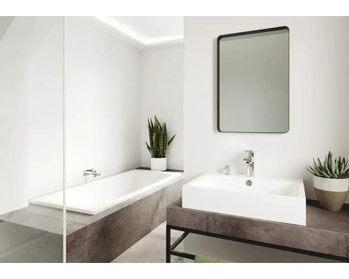 Badkamer met bad, wastafel, spiegel en planten voor een lichte en vriendelijke sfeer.