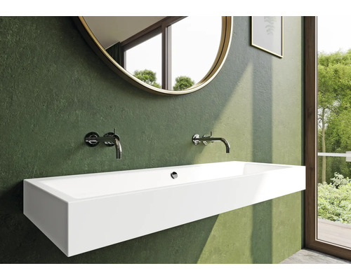 Badkamer met een langwerpige, wandhangende wastafel, kranen en een ronde spiegel