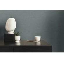 Decoratieve scène met sculptuur, plant en beker op een donkere houten commode voor een effen muur.