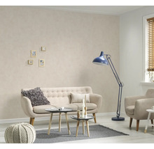 Woonkamer met bank, fauteuil, staande lamp en kleine tafels op een tapijt
