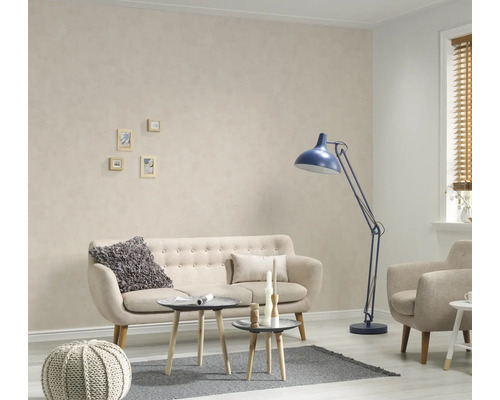 Woonkamer met bank, fauteuil, staande lamp en kleine tafels op een tapijt