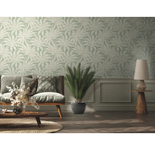 Woonkamer met bank, tafellamp en behang met plantenmotief